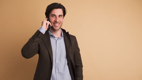 smiling adult businessman talking on smartphone in brown studio
