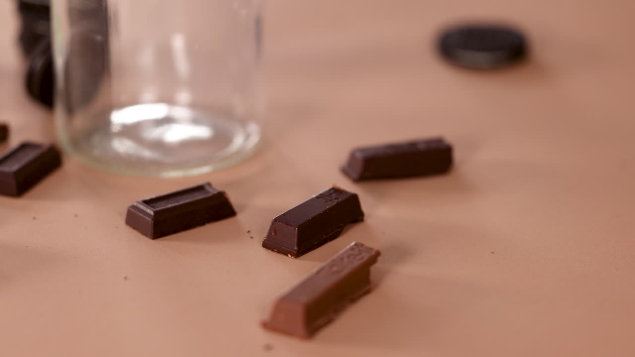 Assorted dark chocolate pieces arranged on brown background, soft lighting, close-up, minimal camera movement