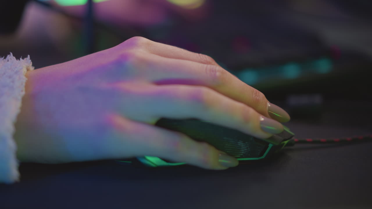 Close up lady hand with polished nail in fluffy sweater using mouse on black pad, illuminated by soft pink and green hue light across fingers and desk