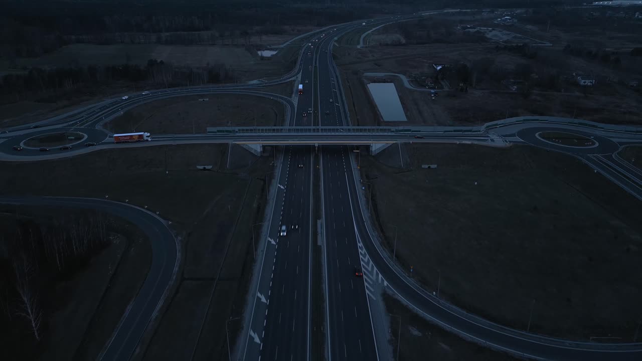 Aerial view of the highway after sunset, crossed by a bridge with on- and off-ramps.