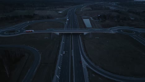 Aerial view of the highway after sunset, crossed by a bridge with on- and off-ramps.