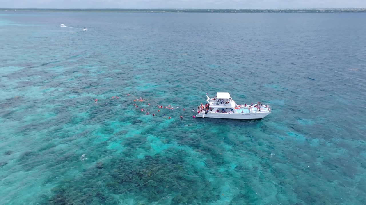 카리브 해 에서 수중 으로 다이빙 하는 스노클러 들 의 그룹 을 보여 주는 관광 보트 를 보여 주는 위 에서 내려온 사진