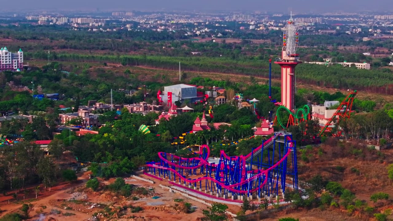 Tòa nhà WONDERLA RESORT với Vòng quay khổng lồ cao chót vót, Tàu lượn siêu tốc Recoil và đất nông nghiệp tại Bannikuppe, Bidadi, Bangalore, Karnataka, Ấn Độ. Ban ngày, góc chụp bán quỹ đạo, chụp bằng drone, 4k