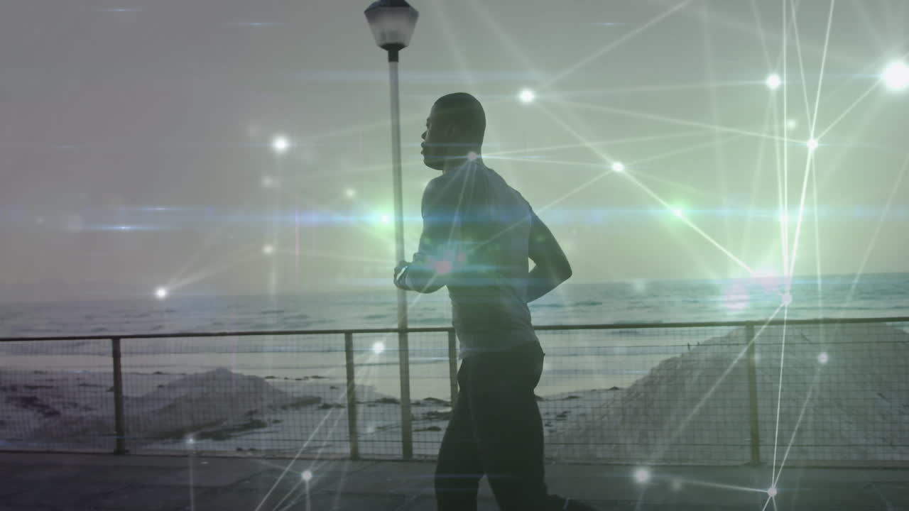 animación de una red de conexiones sobre un hombre afroamericano en forma corriendo en la playa