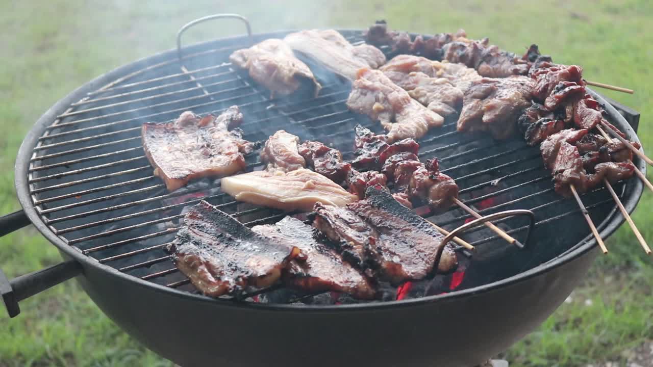 destilando pinchos de pollo con marinada mientras se parrilla en una barbacoa de carbón
