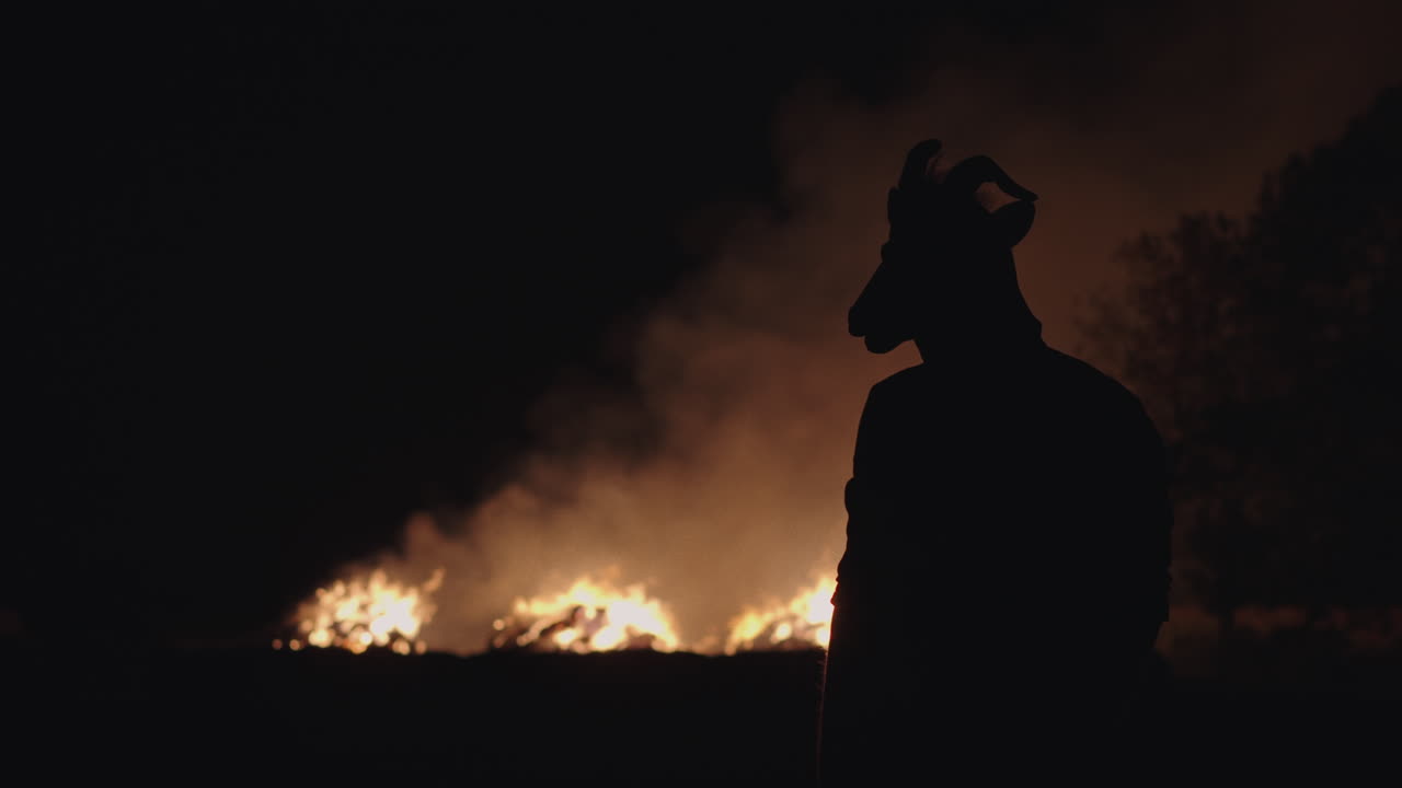 Silhouette di una figura con maschera di capra di notte.