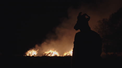 silhouette of a goat-masked figure at night