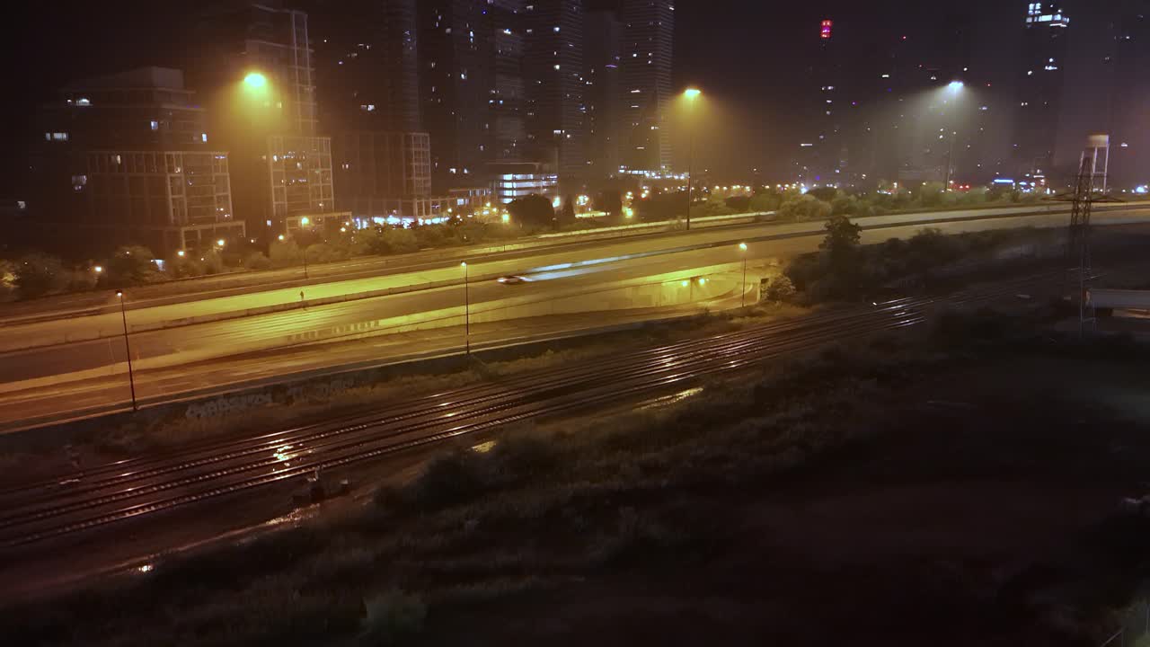 Rising aerial shot moving upwards showing cars driving on Gardiner Expressway at Park Lawn in hazy night of downtown Toronto
