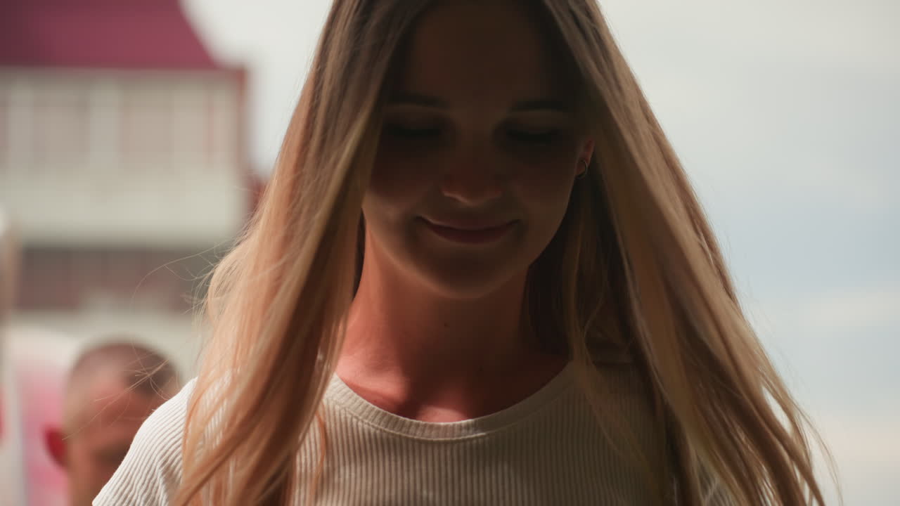 Solbeskinnet bypar ved vogn, kaukasisk kvinde med flettet hår smiler, kaukasisk mand står i nærheden, dekorativ boblevogn draperet i pink stof og blomster, baggrund med murstenslejlighed, varmt