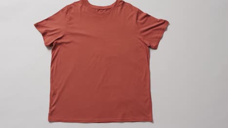 Video-of-flat-lay-of-orange-t-shirt-with-copy-space-on-white-background