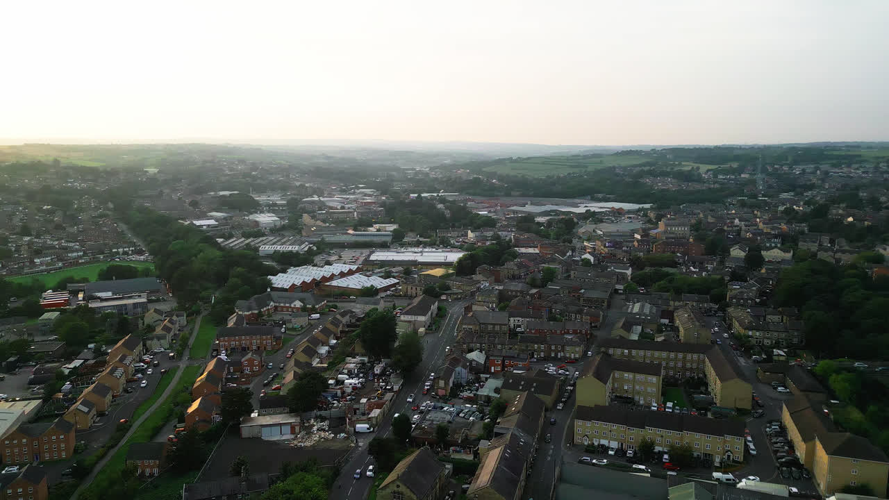 un avión no tripulado registra heckmondwike, reino unido, con edificios industriales, calles bulliciosas y el centro antiguo de la ciudad en una noche de verano
