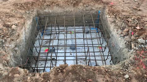 slow tilt up shot of a single foundation in a construction site