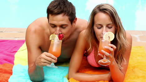 sexy couple lying by the pool on holidays drinking cocktails