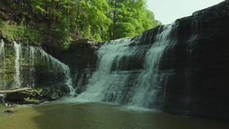 slow lateral pan of upper balls falls waterfall with green forest and cascading water in view