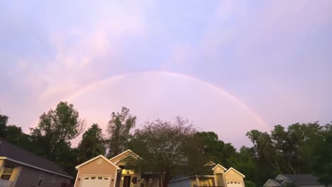 Slow-pan-to-reveal-full-rainbow-above-neighborhood,-wide,-4k