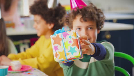 menino dando presente em festa de aniversário com amigos e pais em casa