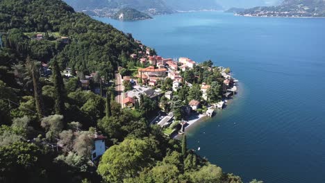 Toma-Aérea-Hacia-Atrás-Que-Muestra-Un-Pequeño-Pueblo-Llamado-Verdana-Bordeando-El-Lago-De-Como-En-Italia-Durante-El-Verano