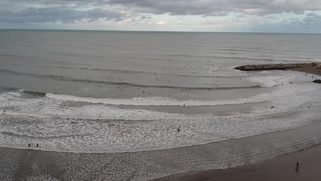 Aerial-view-of-a-beach-full-of-surfers-from-a-drone