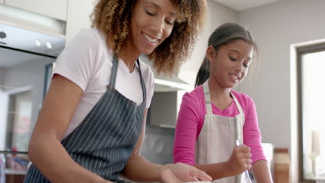 madre y hija biraciales felices besándose mientras hornean en la cocina, en cámara lenta