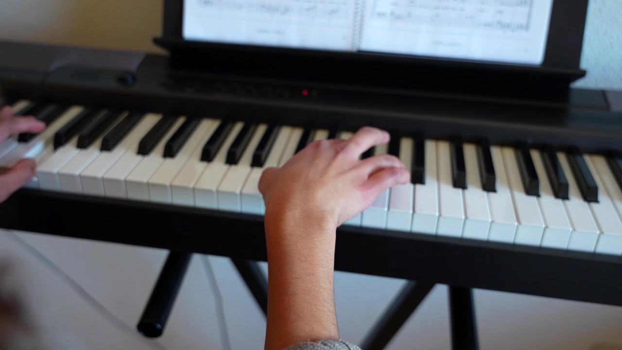 Close up of a young woman's hands playing a beautiful melody on an electric piano at home