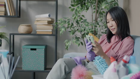woman relaxing and using phone while cleaning