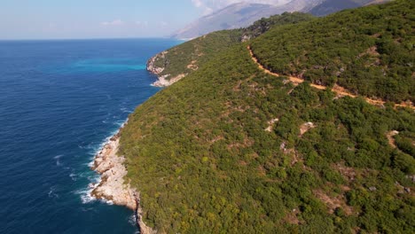 summer colors of mediterranean coastline with green vegetation and blue sea water splashing on rocks