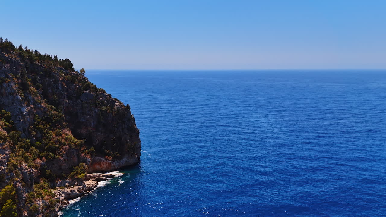 Serene ocean view. Calm blue waters stretch to the horizon, meeting rocky cliffs under a clear sky in a peaceful coastal landscape