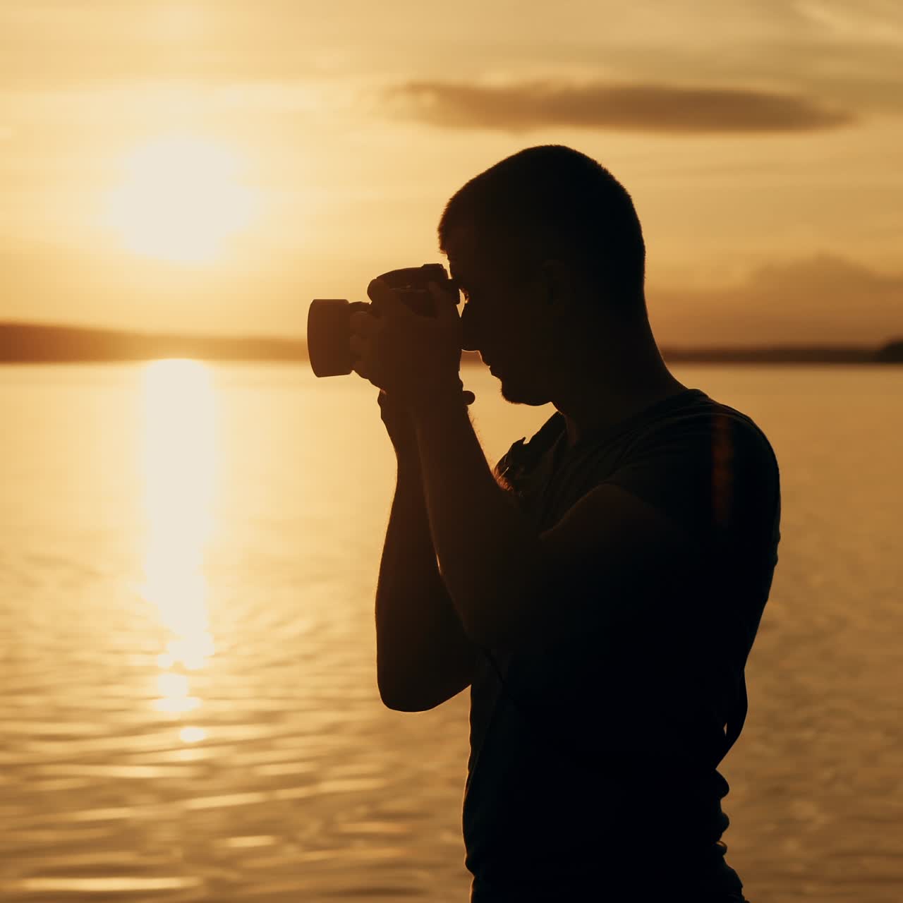 Photographer at the top of a hill by the river. Beautiful summer sunset