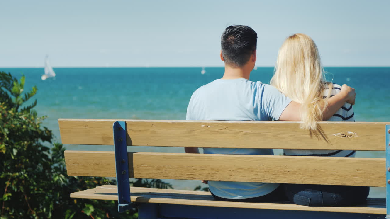 온타리오 호수가 내려다보이는 벤치에서 쉬고 있는 젊은 다민족 부부