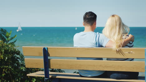 young multi-ethnic couple resting on a bench overlooking lake ontario