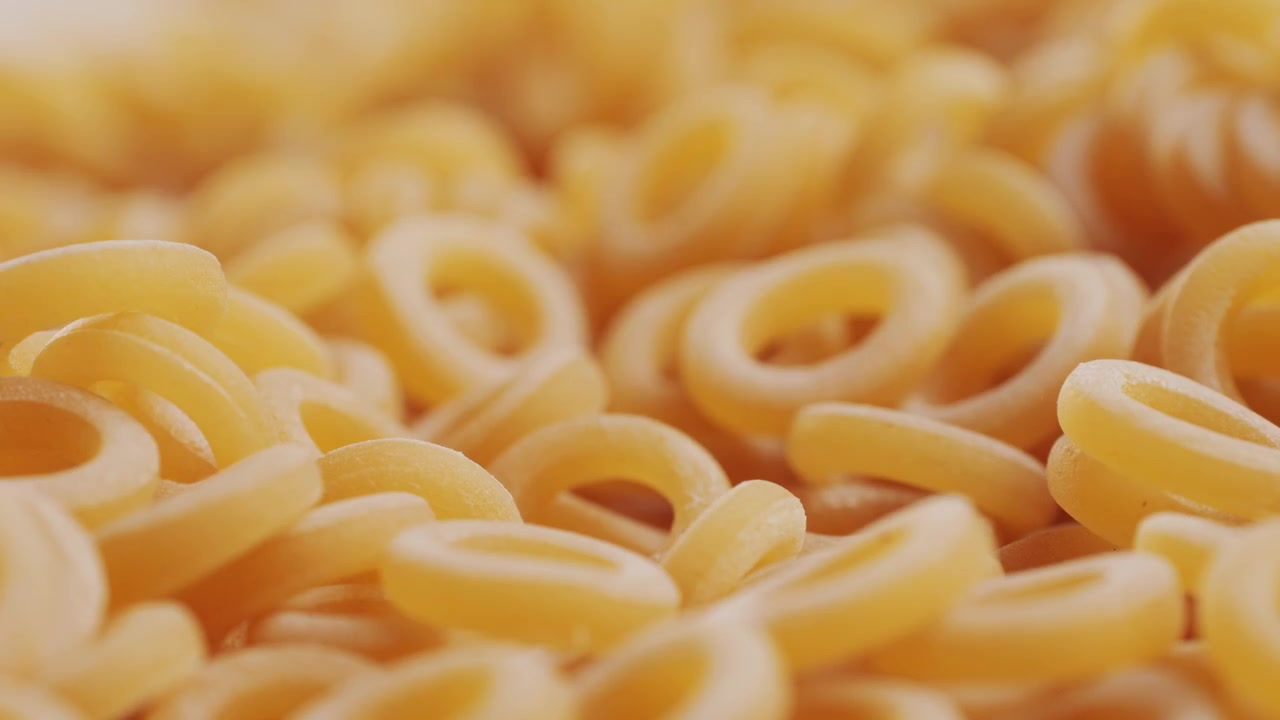 Pasta integrale biologica, maccheroni di semola di grano duro, penne rigate crude in una ciotola di legno. Filmato 4k di alta qualità