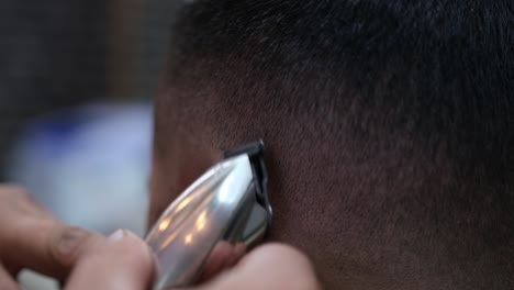 extreme close-up of a barber using an electric razor to give a male customer a very short cut