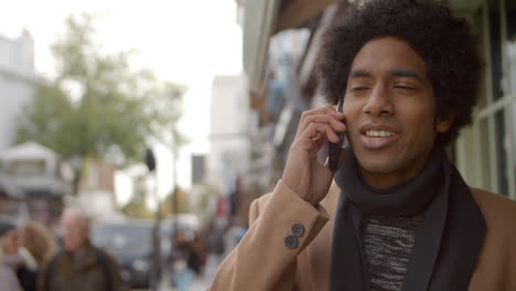 joven usando el teléfono mientras camina por una concurrida calle de la ciudad