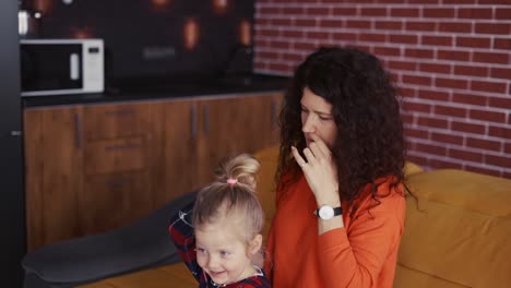 mom is combing the blonde hair for the daughter, making ponytail