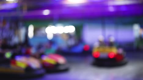 personas disfrutando de coches de parachoques bajo luces coloridas