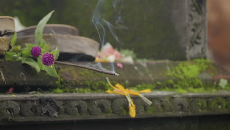 smoke curls from burning incense stick inside ubud palace, bali indonesia