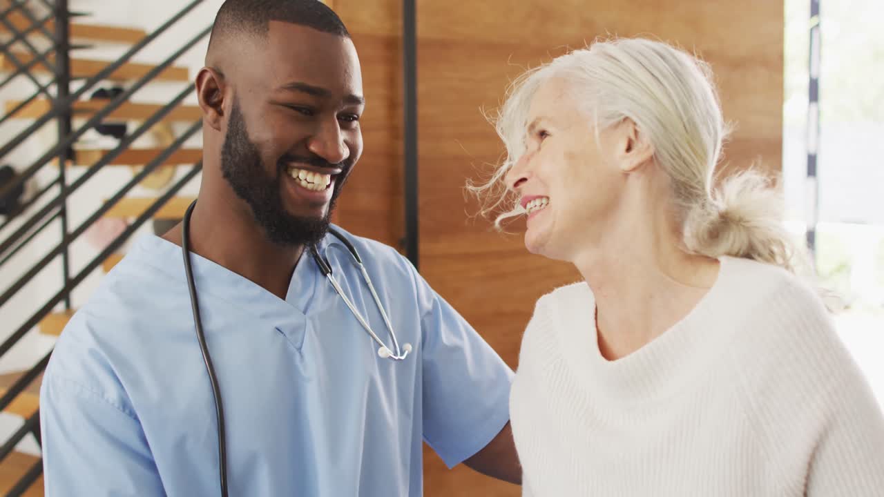 Vidéo d'un médecin afro-américain souriant prenant soin d'une femme âgée caucasienne