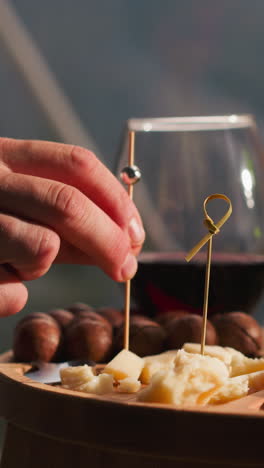man impales cheese onto skewer at small table closeup. gourmet wants to taste new sort of cheese at dinner in restaurant. snack plate for guests