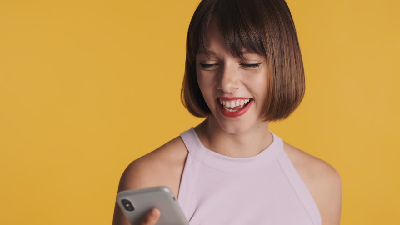 una mujer joven riendo y hablando por teléfono.