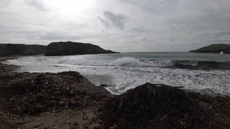 slow motion ocean waves splashing around large rock anglesey shoreline