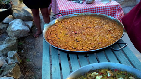 toma en cámara lenta de una gran sartén llena de paella, un plato de arroz español en un pequeño mercado