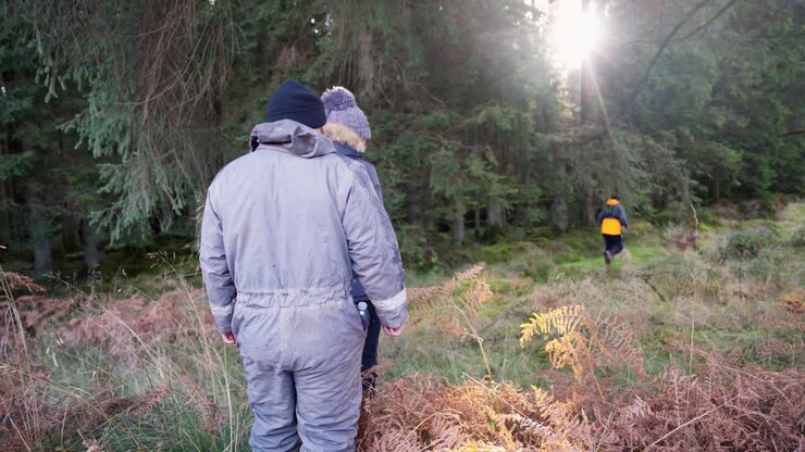 group of friends hiking through forest with no tracks or paths on sunny winter day