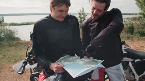 two motocross riders looking at map to find route