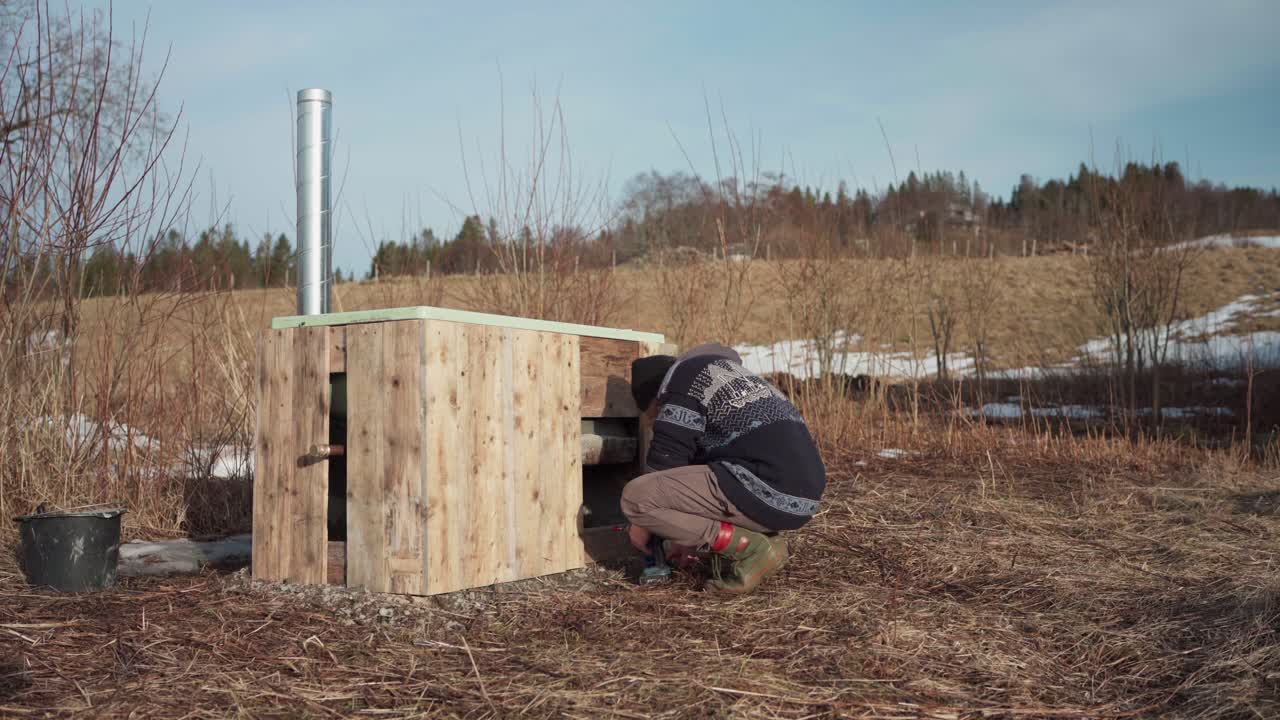 vista de un hombre construyendo una bañera de agua caliente en la naturaleza - toma amplia