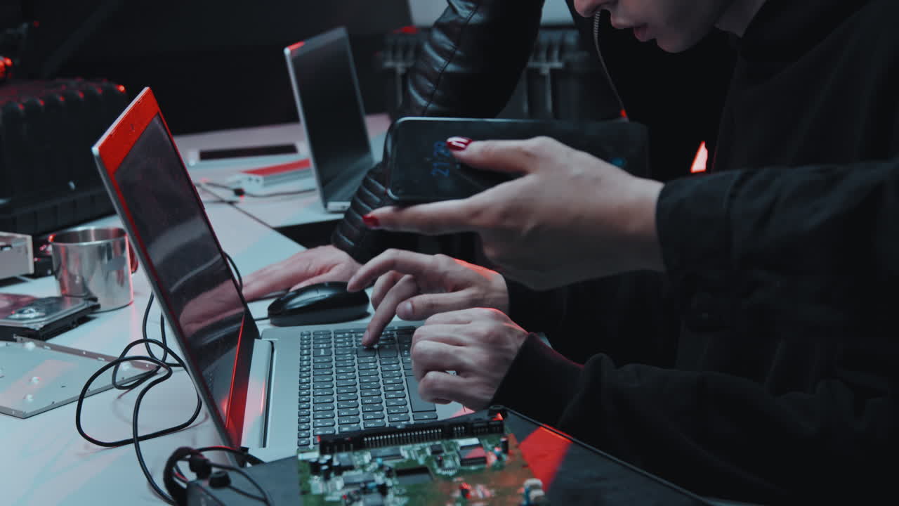 Hackers Talking and Using Laptop in Dark Office