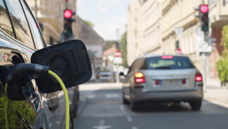 Coche-Eléctrico-Estacionado-En-La-Calle-De-La-Ciudad,-Con-Cargador-Enchufado,-Toma-Manual