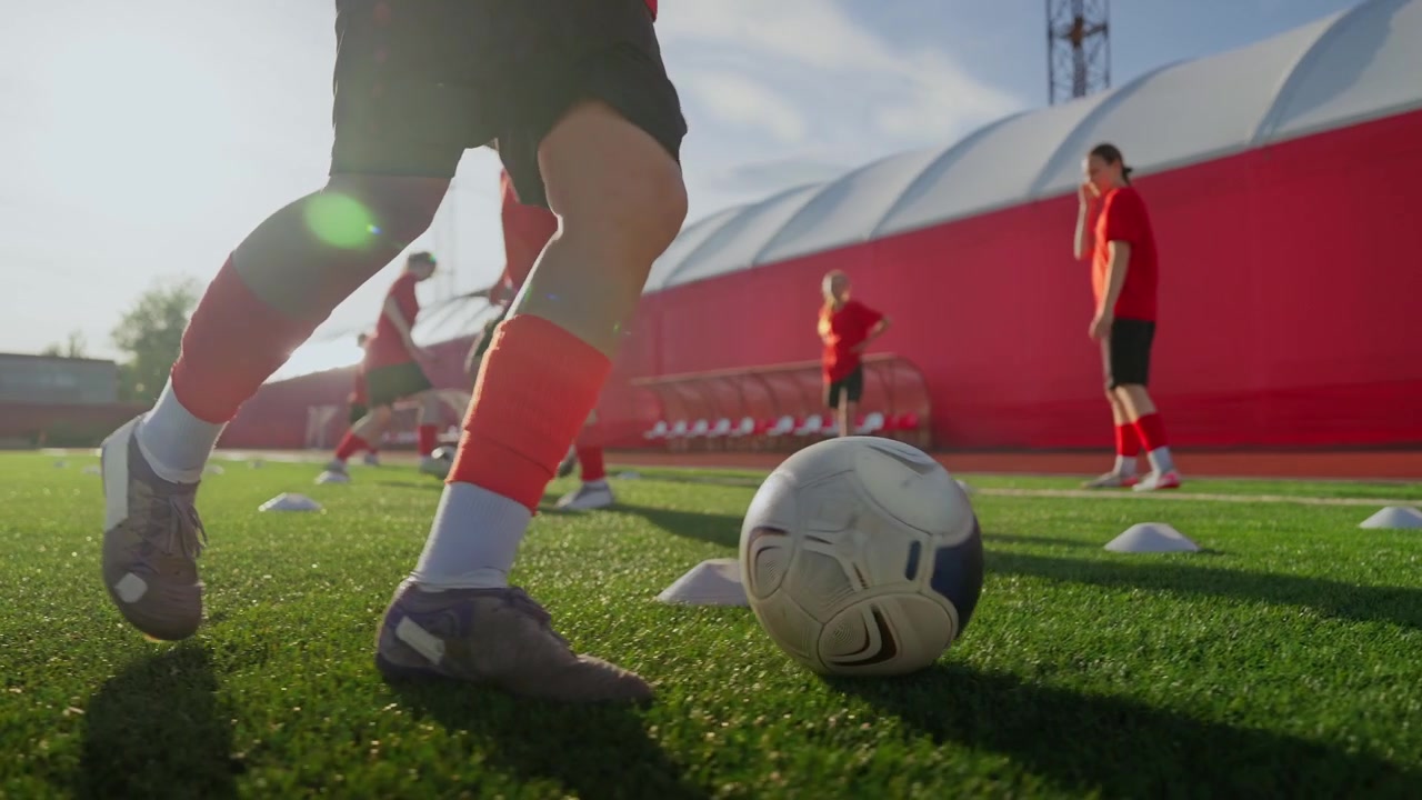 Squadra di calcio giovanile che si allena nel dribbling su un campo all'aperto.