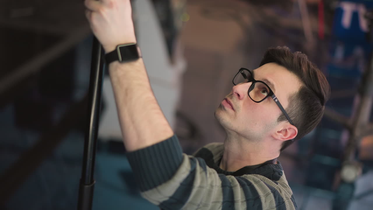 Close-up of man adjusting boom microphone in professional studio environment, focusing on sound recording equipment and crew, preparing for filming process in modern video production setup