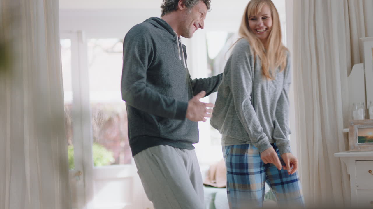 молодая счастливая пара танцует дома, празднует, веселится в выходные утром вместе, наслаждается смешным танцем в спальне, празднует успешные отношения, 4k кадры