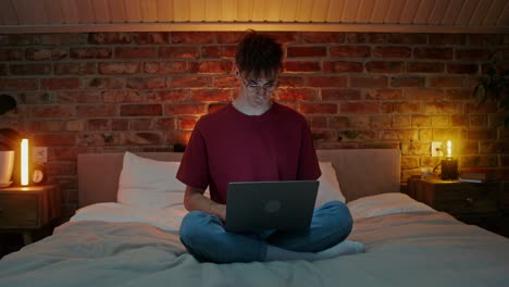 hombre trabajando en la computadora portátil en la cama por la noche